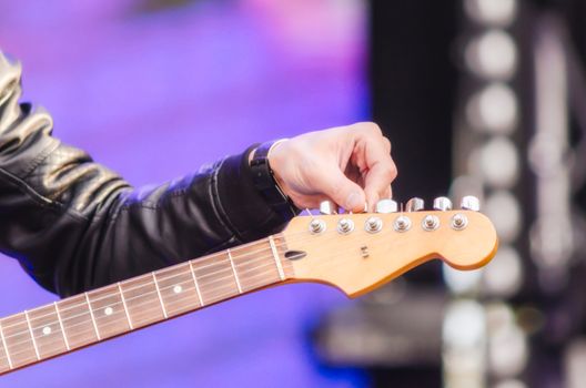 male hand musician tunes guitar closeup