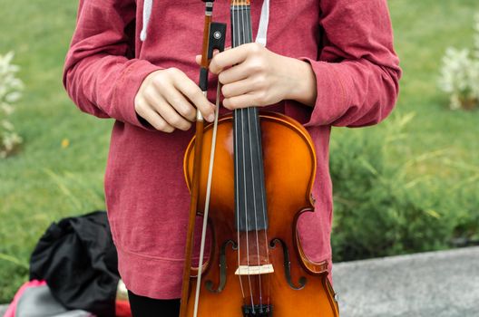 hands of a street musician girl with violin closeup