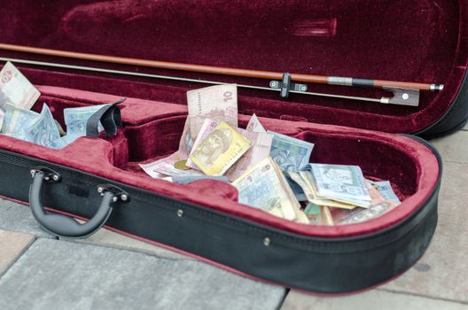 ukrainian money bills in a case of a street musician closeup