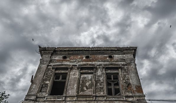 destroyed old building on a gloomy cloudy sky with birds
