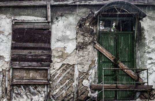 destroyed old building with a boarded up window and a door in the rain