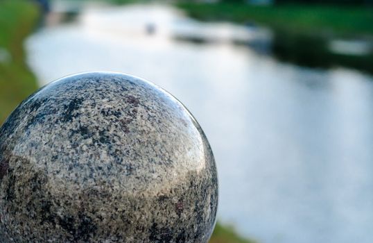 decorative marble ball against the background of the river in the evening