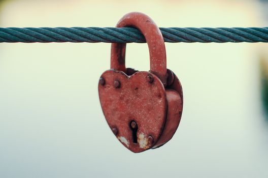 red peeling metal wedding lock on a rope with a key hole