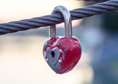 red peeling metal wedding lock on a rope with a key hole