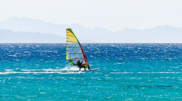 surfer rides in the Red Sea against the backdrop of a rocky coast in Egypt