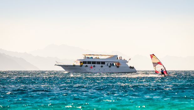 big boat and a surfer in the sea on the background of a rocky coast in Egypt Dahab