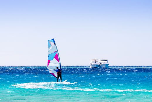 surfer rides in the Red Sea against the backdrop of two ships in Egypt Dahab