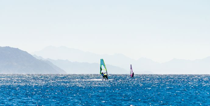 surfers ride in the Red Sea in Egypt against the backdrop of the rocky coast