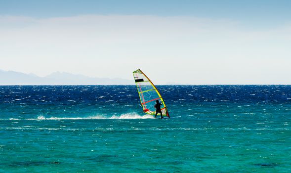 windsurfer on the background of mountains rides on the waves of the Red Sea in Egypt Dahab