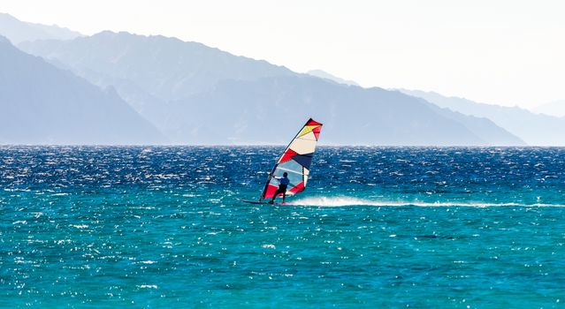 surfer rides in the Red Sea against the backdrop of a rocky coast in Egypt