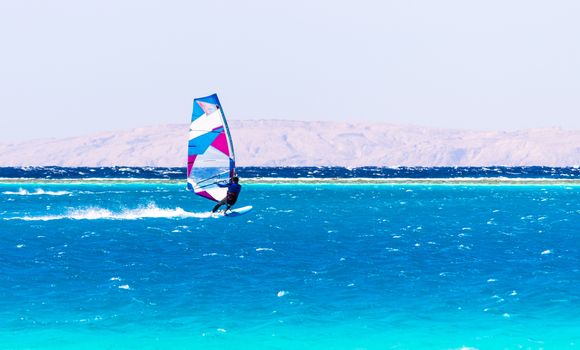 surfer rides in the Red Sea on the background of the rocky coast in Egypt Dahab