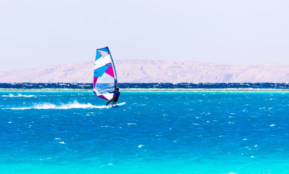 surfer rides in the Red Sea on the background of the rocky coast in Egypt Dahab