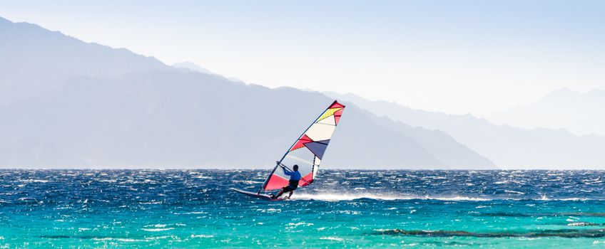 surfer rides in the Red Sea on the background of the rocky coast in Egypt Dahab