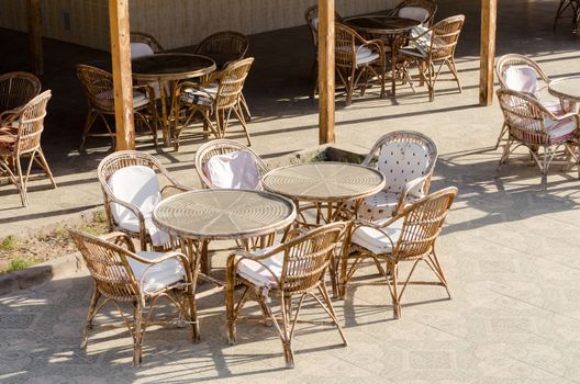 wooden chairs and round tables in an empty hotel cafe