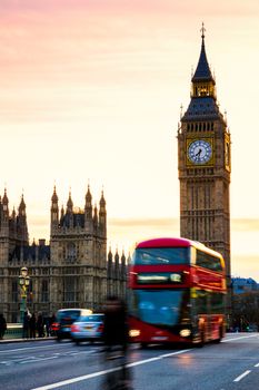 Big Ben with the Houses of Parliament and a red double-decker bus passing at dusk