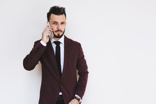 Trendy and fashionable businessman posing on a white background and talking on the phone.