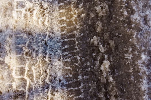 car tire imprint on snow covered road, sunny day