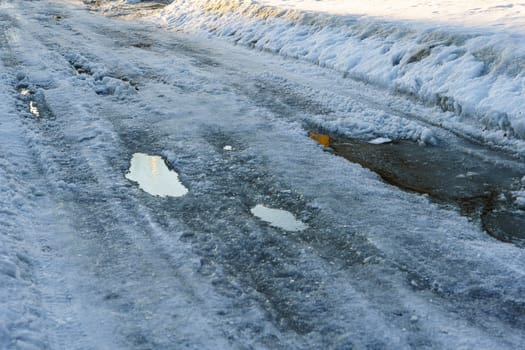 road covered with snow and ice with ruts on the street of the provincial Russian city