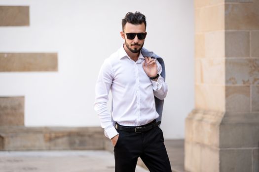 Portrait of elegant and fashionable man in black sunglasses posing on the street