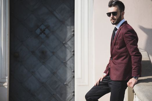 Elegant fashionable man in black sunglasses posing outdoor on the stairs (copy space).