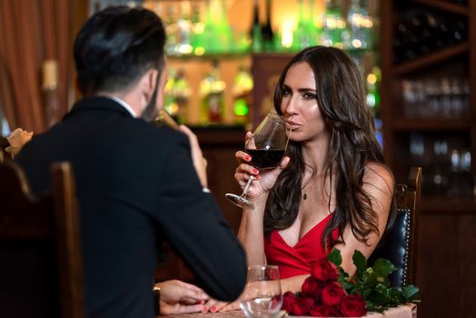 Attractive couple in love is dating and drinking wine during romantic dinner in the restaurant.