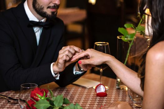 Man surprising woman with engagement ring during romantic dinner at the restaurant in close-up