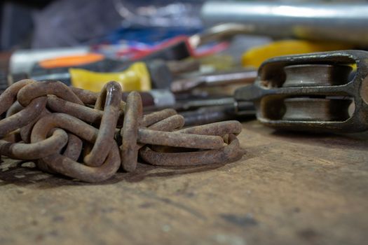 Table of a mechanical and electrician workshop, with an old chain and another tools on top