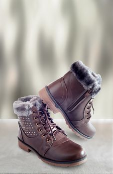 Comfortable and warm winter boots with gray fur inside, zipper and lace-up. Presented on a light background.