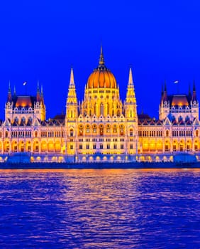 The Hungarian Parliament Building located on the Danube River in Budapest Hungary at sunset.