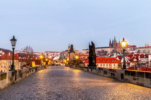Prague, Czech Republic. Charles Bridge with its statuette and sunrise over the bridge, Old Town Bridge Tower in the background.