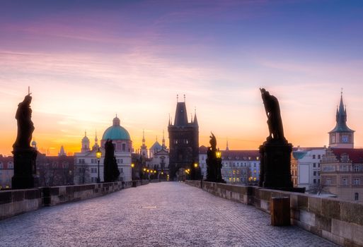 Prague, Czech Republic. Charles Bridge with its statuette and sunrise over the bridge, Old Town Bridge Tower in the background.