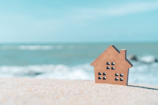 Model of a little house on sand with nature beach background. Dream life concept.