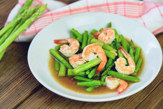 Asparagus Shrimp Seafood Cooked Health Food / Stir fried shrimps with asparagus green on white plate and wooden table background