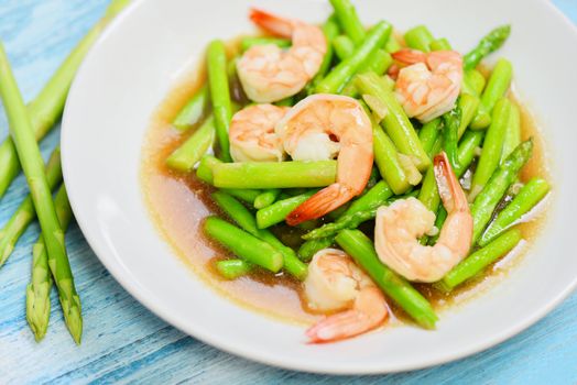 Asparagus Shrimp Seafood Cooked Health Food / Stir fried shrimps with asparagus green on white plate and wooden table background