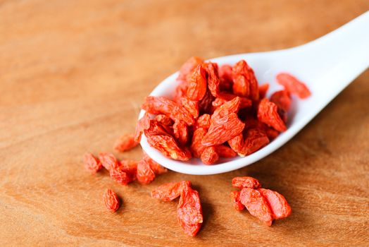 goji berry dry spices and herbs dood ingredients / goji berries on white spoon and wooden background 