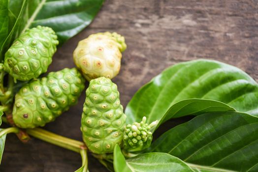 noni fruit on wooden background / fresh ripe and raw noni leaf , Great morinda (Noni) or Morinda citrifolia