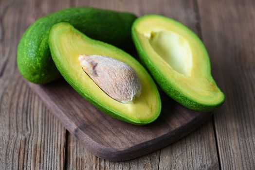 Avocado sliced half on wooden cutting board for avocado salad / Fruits healthy food concept