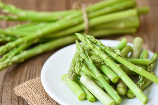 Asparagus on white plate and wooden background / Fresh green asparagus sliced for cooking food 