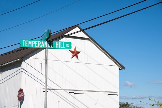 Red Mennonite star of exterior of simple white building by Temperance Hill Road street sign.