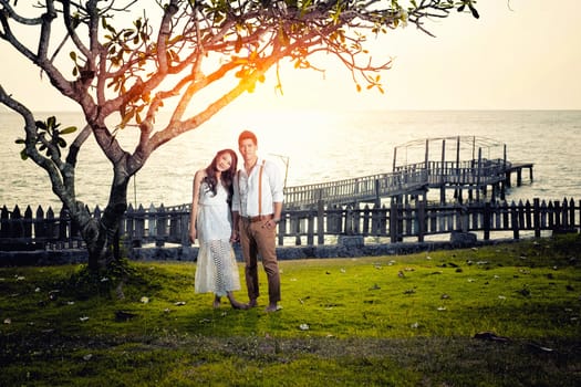 Happy couple relaxing in a tree by the sea