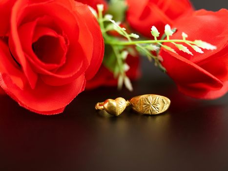 Wedding celebration on valentines day with red rose bouquet, wedding rings, isolated on dark background. Concept of love and romance.