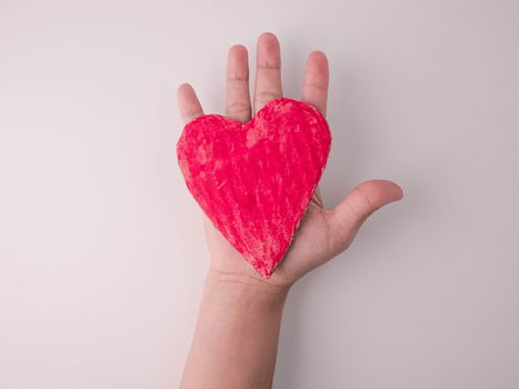 A red heart-shaped cardboard placed on the hand, isolated on white background. Concept of love and valentines day.