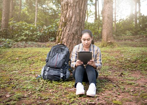 Young woman traveler searches GPS coordinates by tablet PC at nature trail in summer vacations day. Technology and Travel concept.