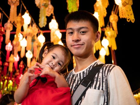 Happy Asian family standing over light from Thai lanna lanterns background at night in Yi Peng Festival.