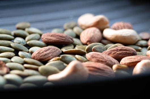 Nuts mix (almond, cashew and pumpkin seeds) for a healthy diet on black background.