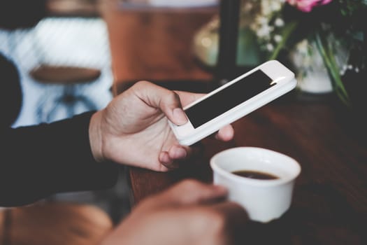 Womanhand using smartphone to do work business, social network, communication in public cafe work space area.