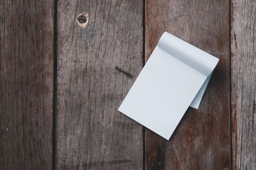 Small white notebook on old grunge wood texture background.