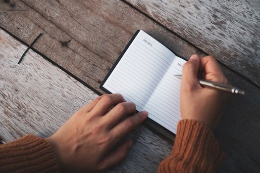 Copy space of woman hand writing down in white notebook with colorful bokeh background.