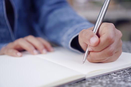 Copy space of woman hand writing down in white notebook with colorful bokeh background.