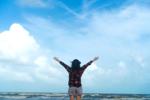 Woman rise hands up to sky freedom concept with blue sky and summer field background.